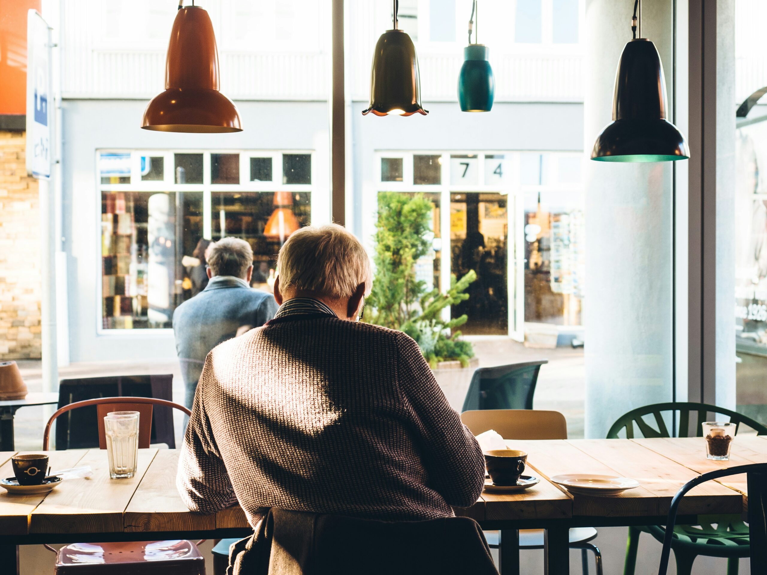Elderly person sitting in a cozy café-style room, representing senior living facilities and the need for strong mobile connectivity