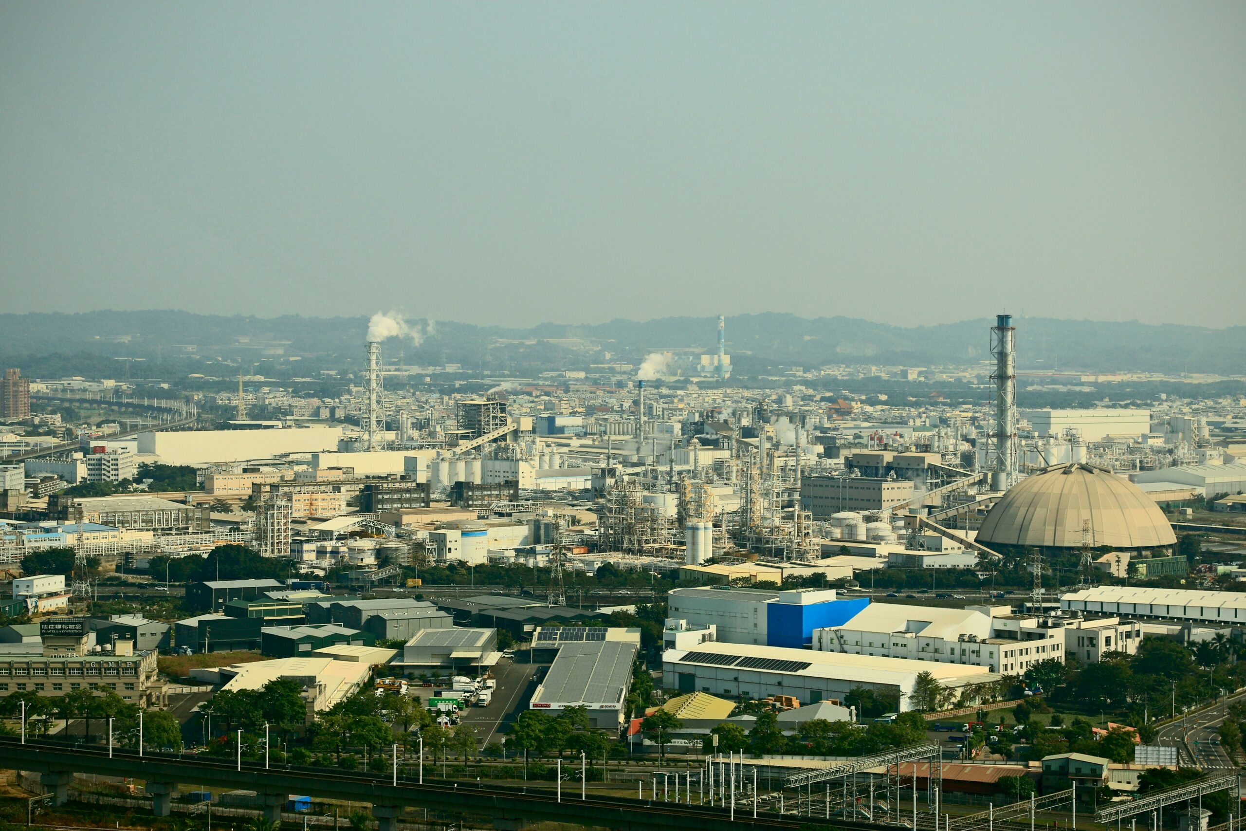 Wide aerial view of an industrial site with factories and chimneys, illustrating private 5G deployment in manufacturing environments