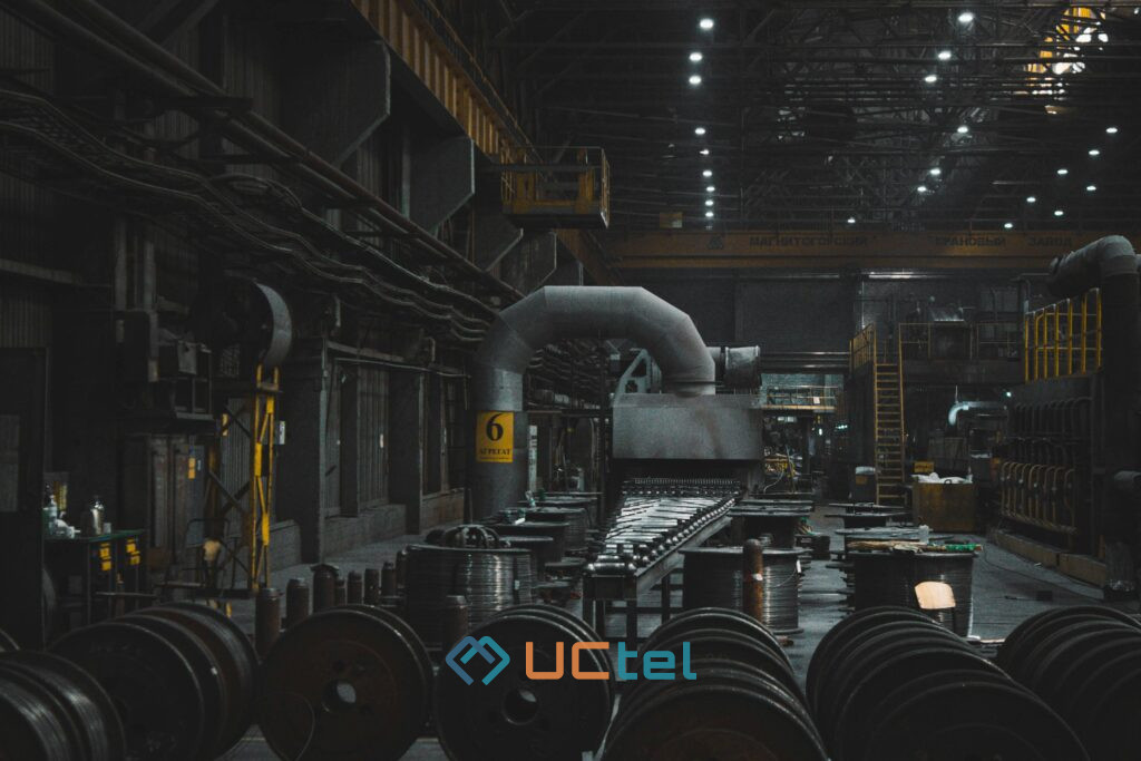 Dark industrial factory interior with heavy machinery and steel coils, illustrating signal booster monitoring in harsh environments